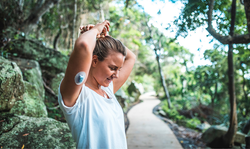 Person in the woods wearing an arm blood glucose monitor